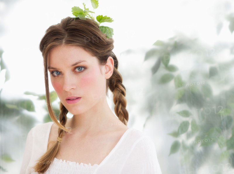 Studio portrait of young woman with leaves in hair.