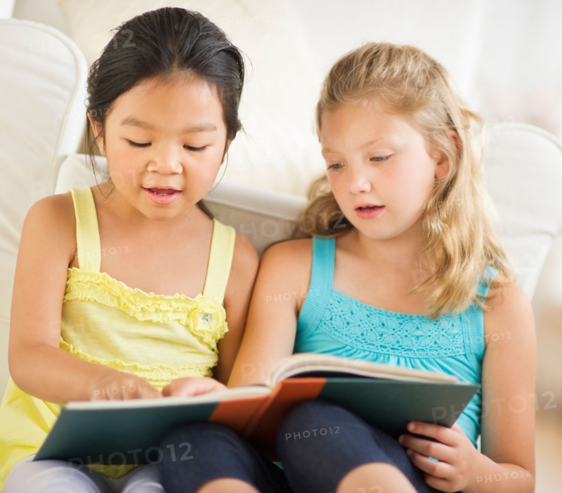 two girls (6-9) reading book.