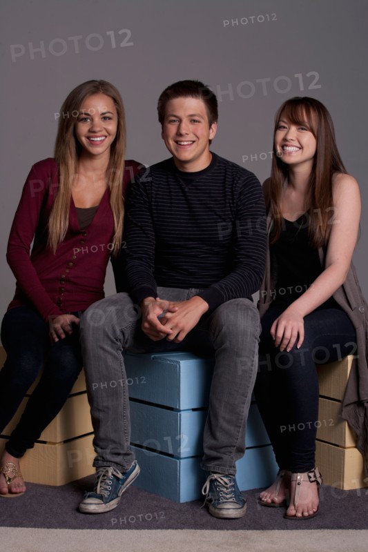 Portrait of teenage boy (16-17) and girl (16-17) with young friend, studio shot. Photo: Rob Lewine