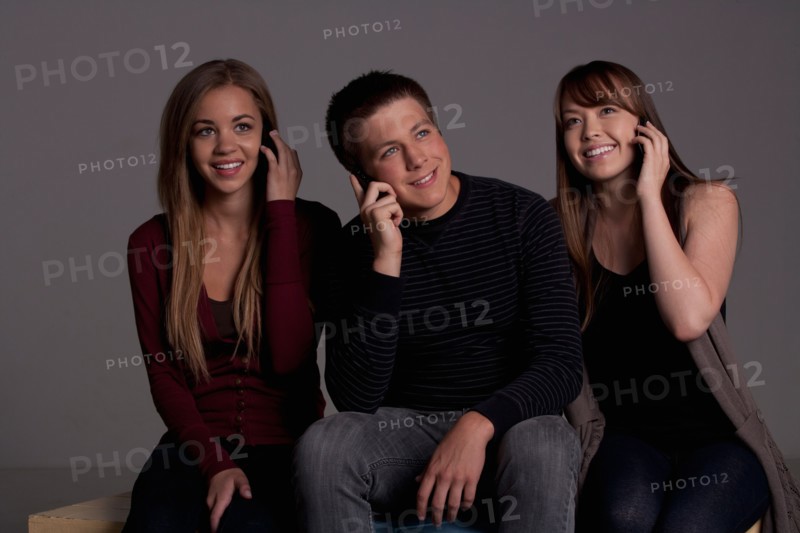 Portrait of teenage boy (16-17) and girl (16-17) with young friend, studio shot. Photo : Rob Lewine