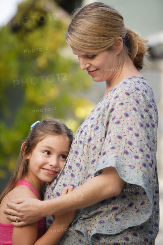 Pregnant mother and daughter (6-7) embracing . Photo: Rob Lewine