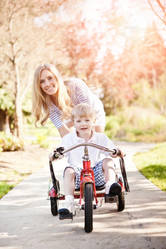 Mother and son (2-3) riding tricycle in park. Photo: Take A Pix Media