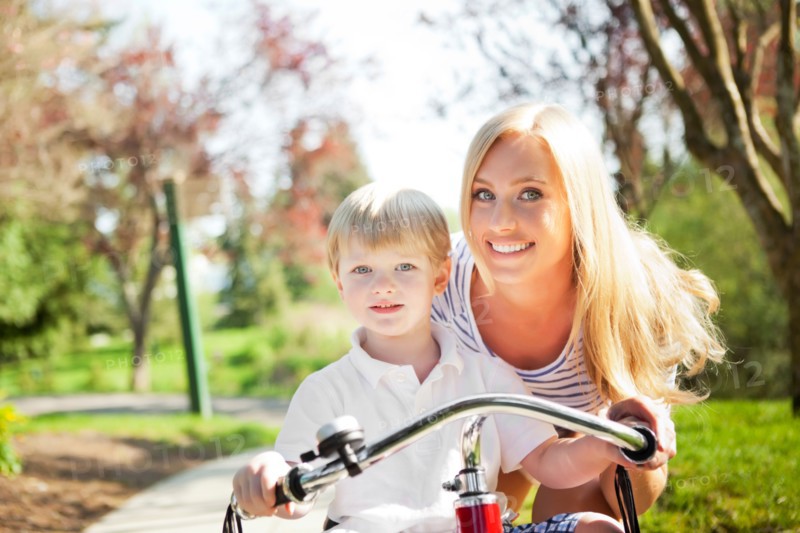 Mother and son (2-3) riding tricycle in park. Photo : Take A Pix Media