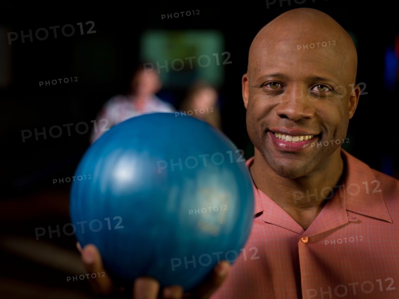 Smiling mature man holding bowling ball. Photo: db2stock