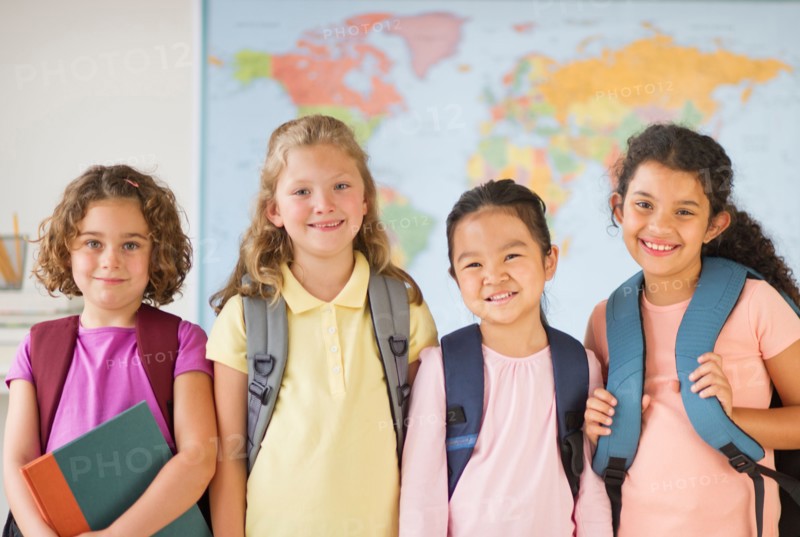 Portrait of four girls (6-9) carrying backpacks.
