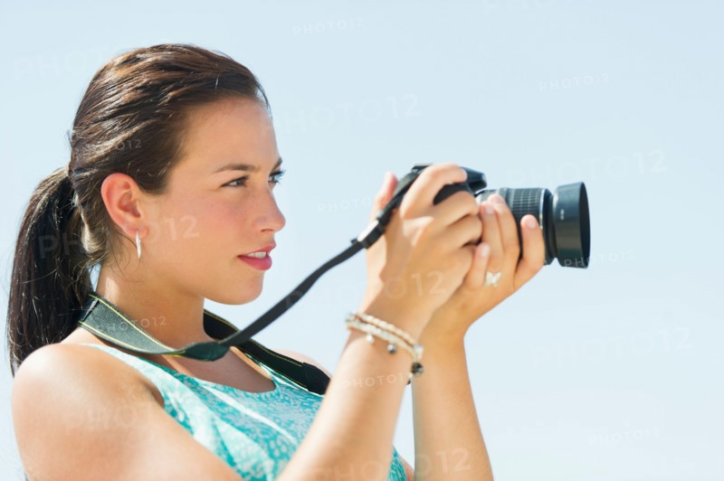 Portrait of young woman taking pictures with camera.