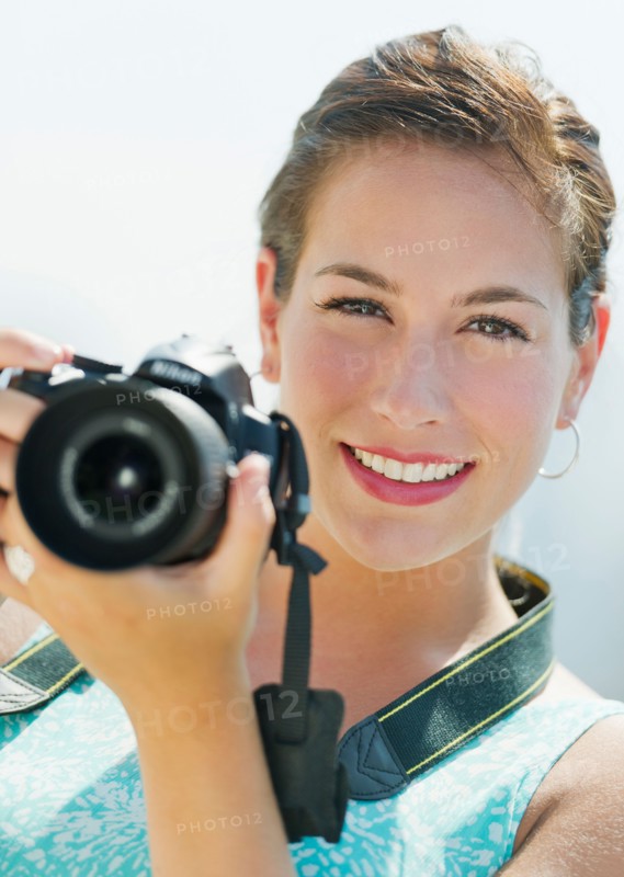 Portrait of young woman taking pictures with camera.