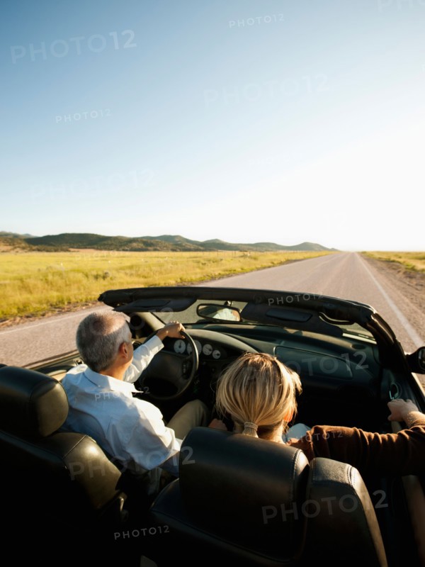 USA, Utah, Kanosh, Mad-adult couple driving through desert plains in convertible car. Photo: Erik Isakson