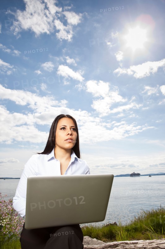 Young businesswoman using laptop on lakeshore. Photo : Take A Pix Media