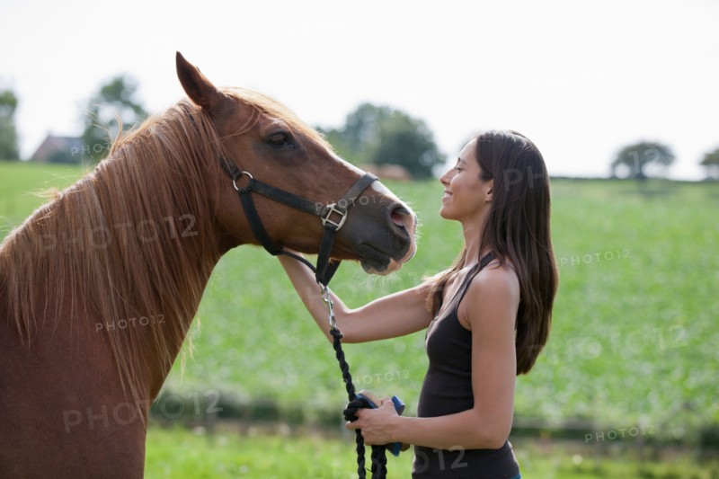Young woman with horse in field. Photo: Jan Scherders