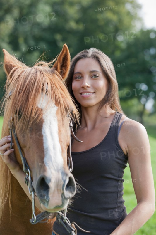 Portrait of young woman with horse in field. Photo: Jan Scherders