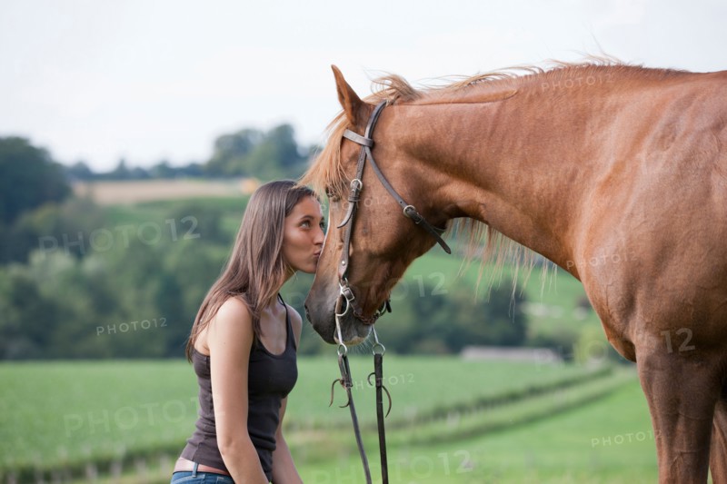Young woman kissing horse in field. Photo: Jan Scherders