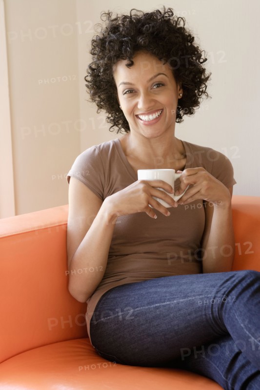 Portrait of young woman sitting on sofa. Photo : Rob Lewine