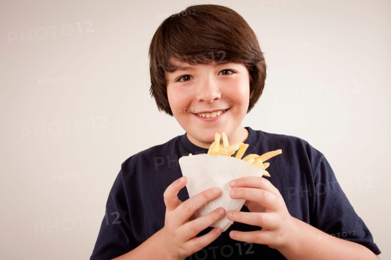Studio portrait of boy (10-11) holding french fries. Photo: Rob Lewine