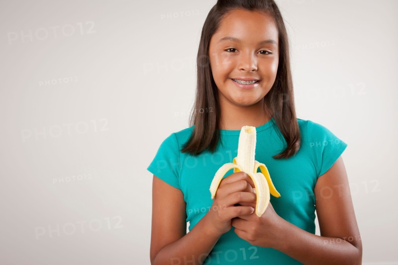 Studio portrait of girl (10-11) holding banana. Photo : Rob Lewine