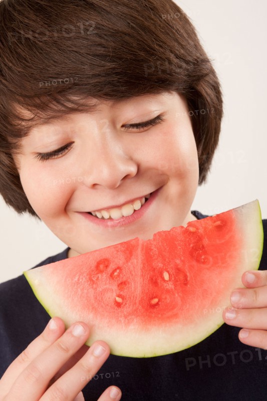 Studio portrait of boy (10-11) eating watermelon. Photo : Rob Lewine