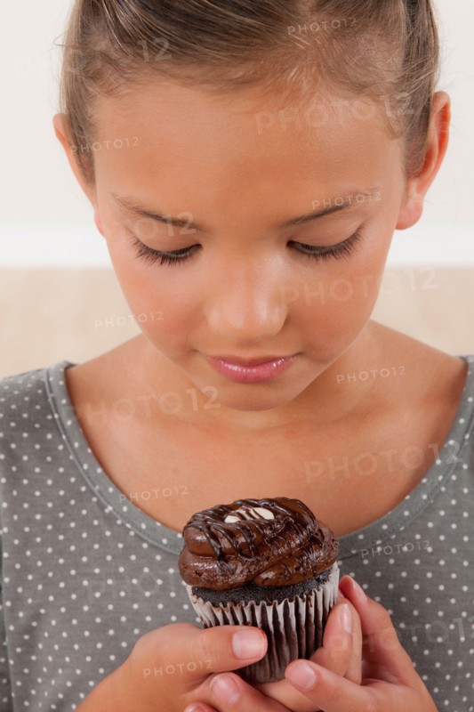 Studio portrait of girl (8-9) holding cake. Photo : Rob Lewine