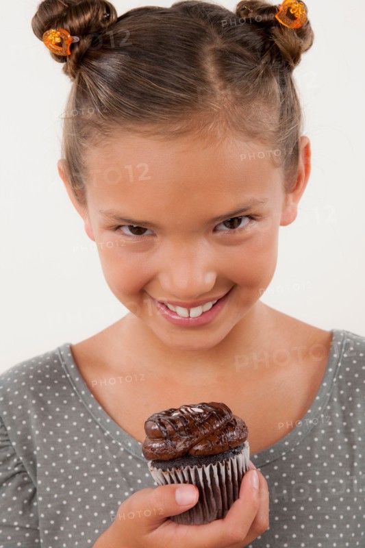 Studio portrait of girl (8-9) holding cake. Photo : Rob Lewine