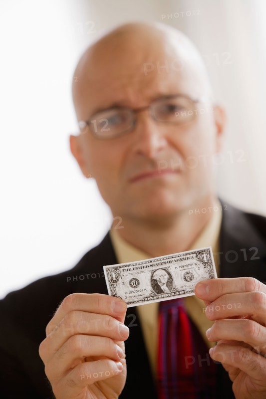 Portrait of business man holding one dollar bill. Photo : Rob Lewine