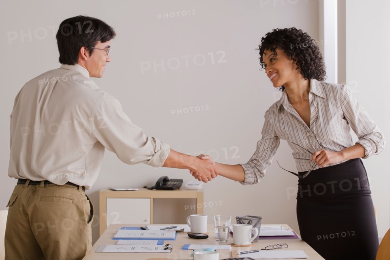 Businessman and businesswoman handshake during meeting. Photo: Rob Lewine