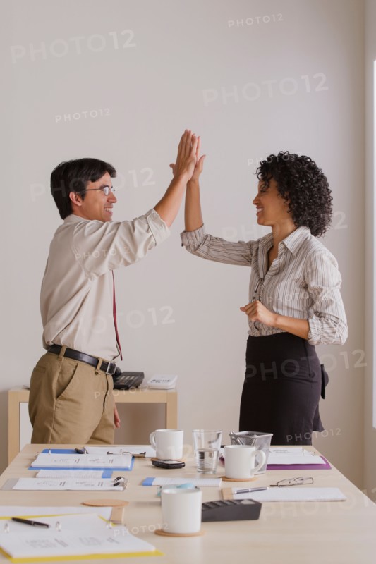 Businessman and businesswoman high fiving. Photo: Rob Lewine