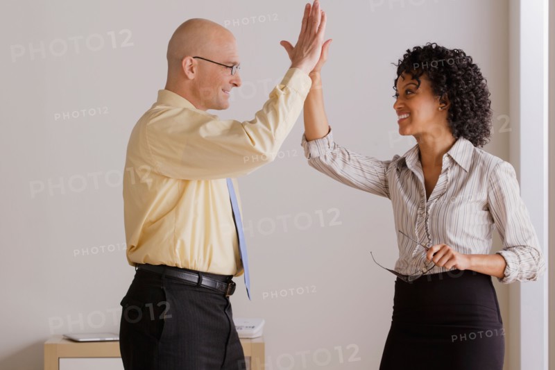 Businessman and businesswoman high fiving. Photo : Rob Lewine