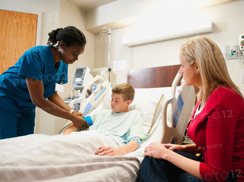 Nurse checking blood pressure to boy (10-11), mother is sitting next to bed. Photo: Erik Isakson
