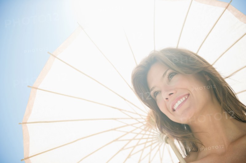 Woman in sunlight with parasol. Photo : Jamie Grill