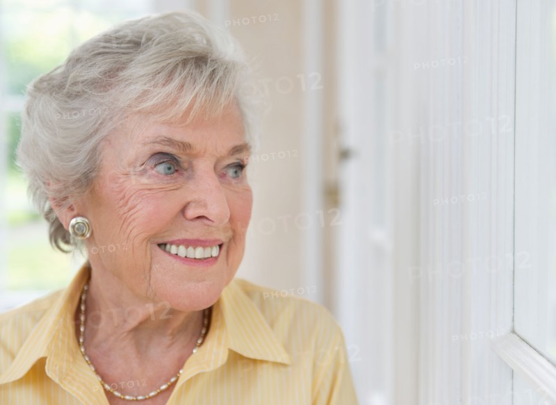 Portrait of senior woman looking through window.