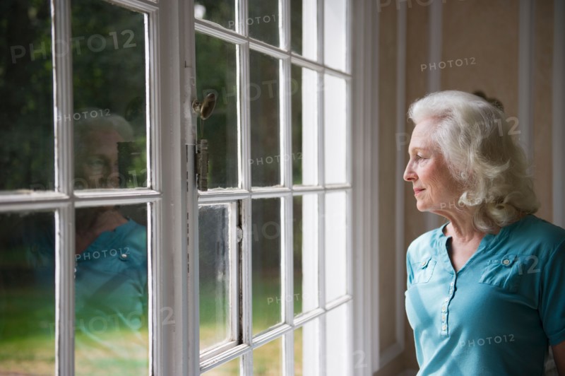 Senior woman looking through window.