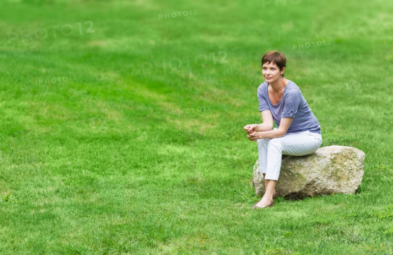 Mature woman sitting on rock.