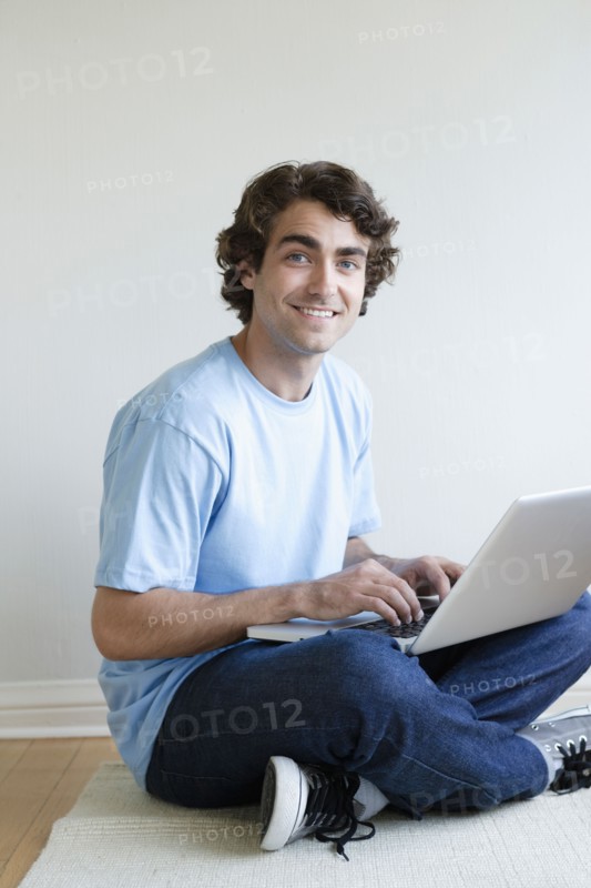 Young man sitting in room using laptop. Photo: Rob Lewine