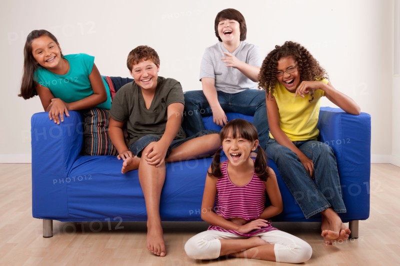 Group of children (10-11, 12-13) sitting on sofa, studio shot. Photo: Rob Lewine