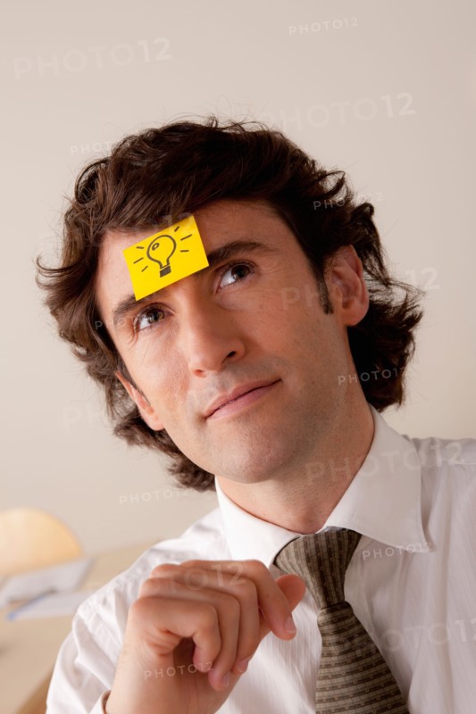 Studio portrait of businessman with adhesive note on forehead. Photo: Rob Lewine
