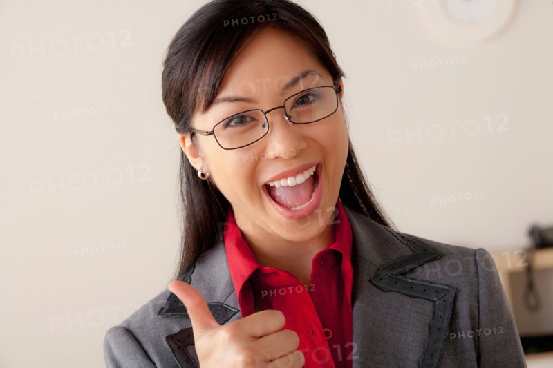 Studio portrait of businesswoman showing thumbs-up. Photo: Rob Lewine
