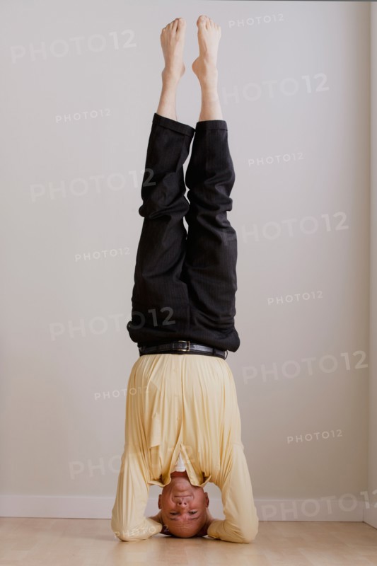 Mature businessman doing headstand. Photo: Rob Lewine
