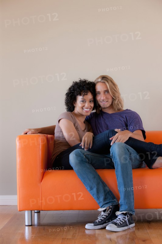 Portrait of young couple sitting on sofa. Photo : Rob Lewine