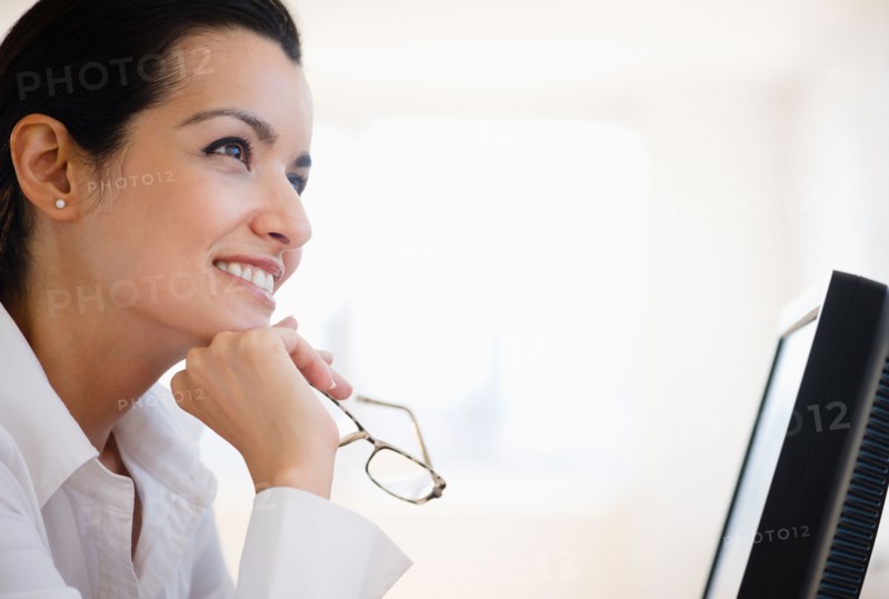 Businesswoman daydreaming at desk in office. Photo: Jamie Grill