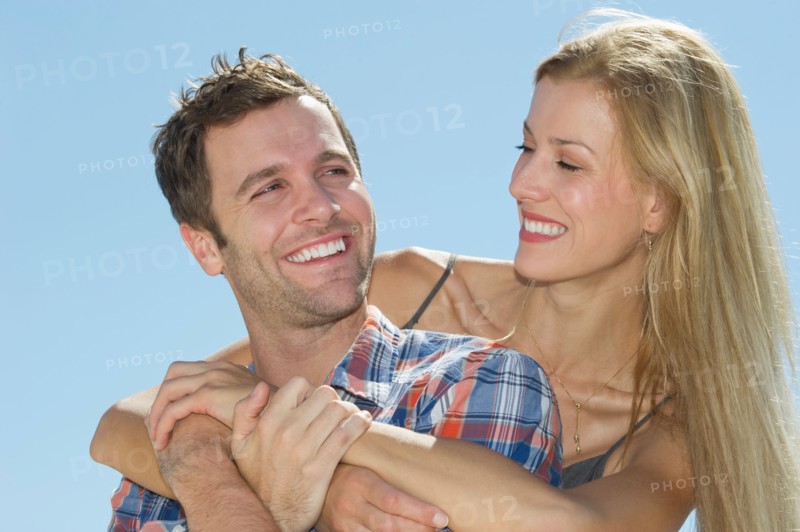 Portrait of mid adult couple against blue sky.