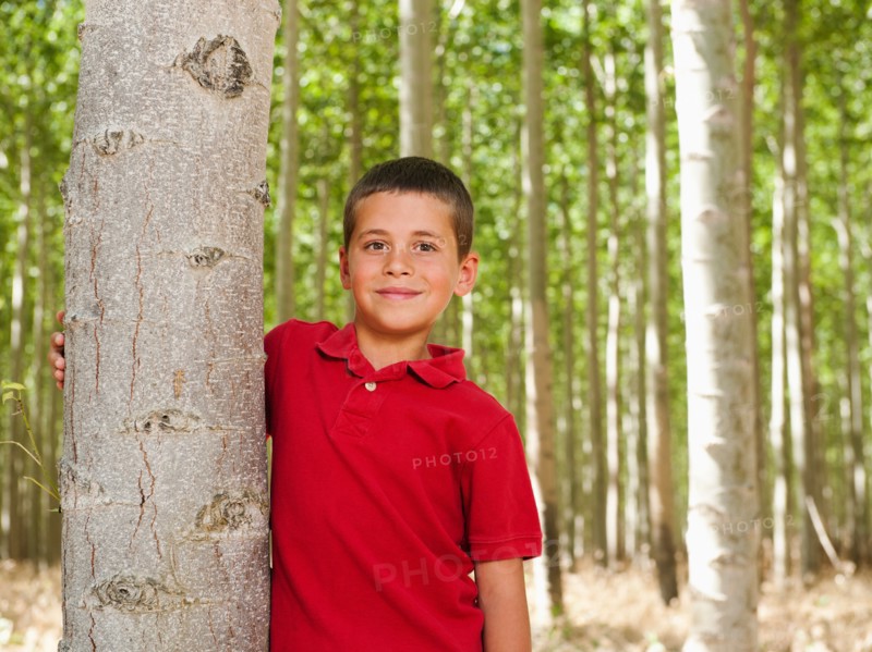 USA, Oregon, Boardman, Boy (8-9) standing between poplar trees in tree farm. Photo: Erik Isakson