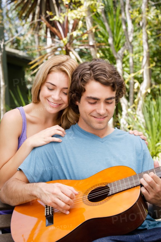 Young couple in park, man playing guitar. Photo: Rob Lewine
