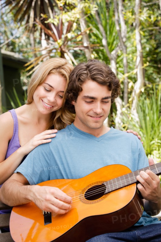 Young couple in park, man playing guitar. Photo: Rob Lewine