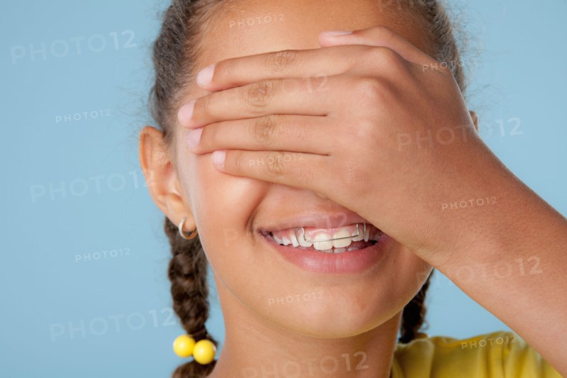 Studio shot of girl (10-11) covering eyes with hand. Photo: Rob Lewine