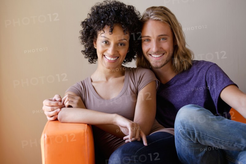 Portrait of young couple sitting in armchair. Photo : Rob Lewine