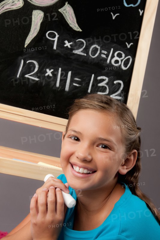 Studio portrait of girl (8-9) next to blackboard. Photo : Rob Lewine