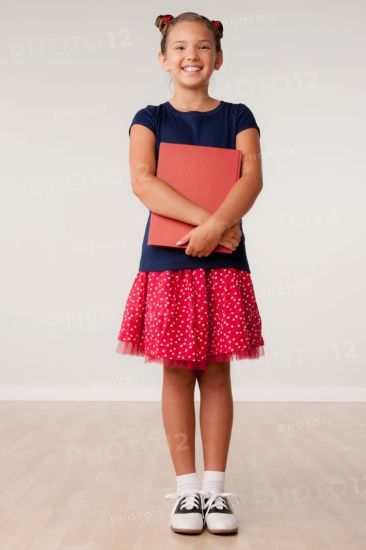 Studio portrait of girl (8-9) holding book. Photo: Rob Lewine