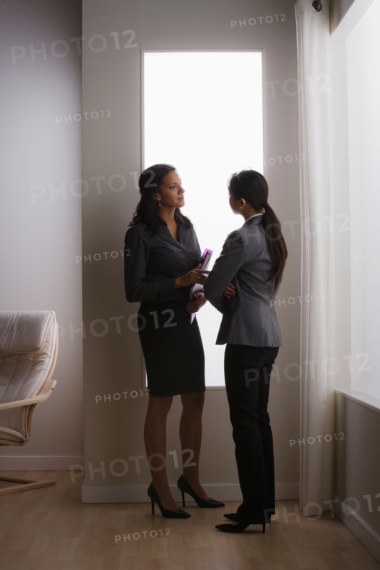 Two business women discussing in office. Photo : Rob Lewine