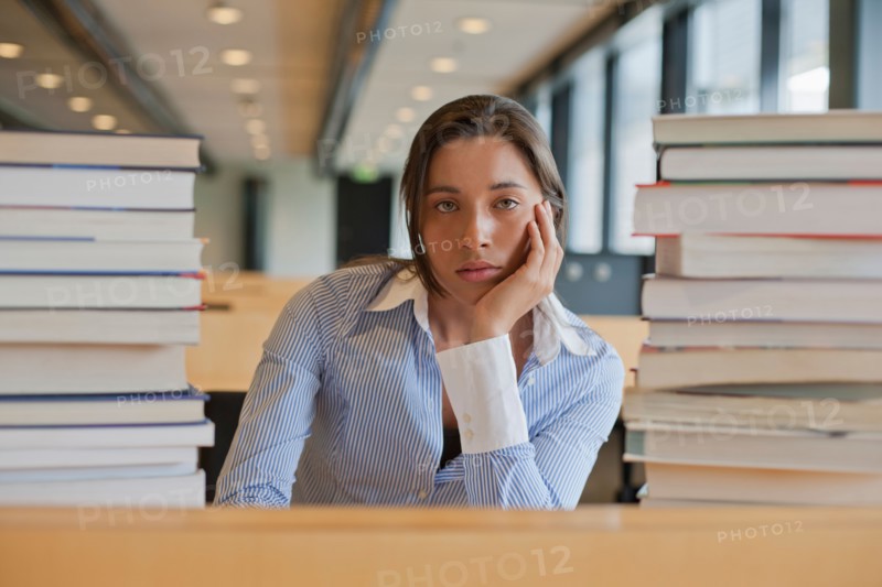 Portrait of female student between stacks of books. Photo : Jan Scherders