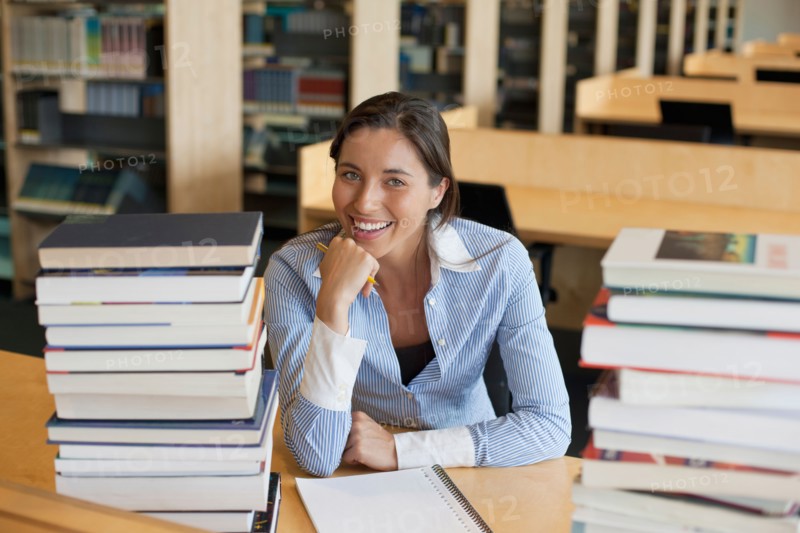 Portrait of female student with books in library. Photo : Jan Scherders