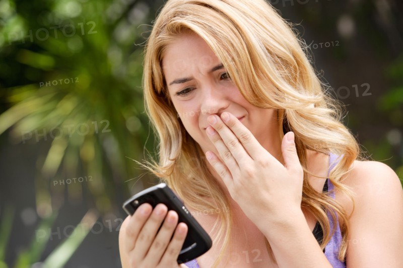 Young woman text-messaging, with facial expression. Photo: Rob Lewine